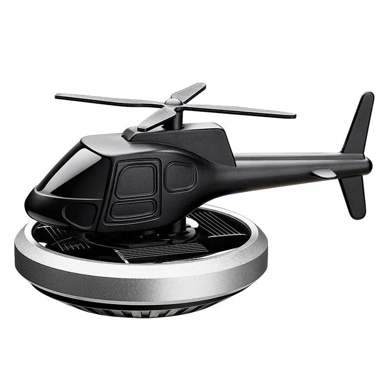 Silver metal solar-powered helicopter car air freshener rotating on a dashboard