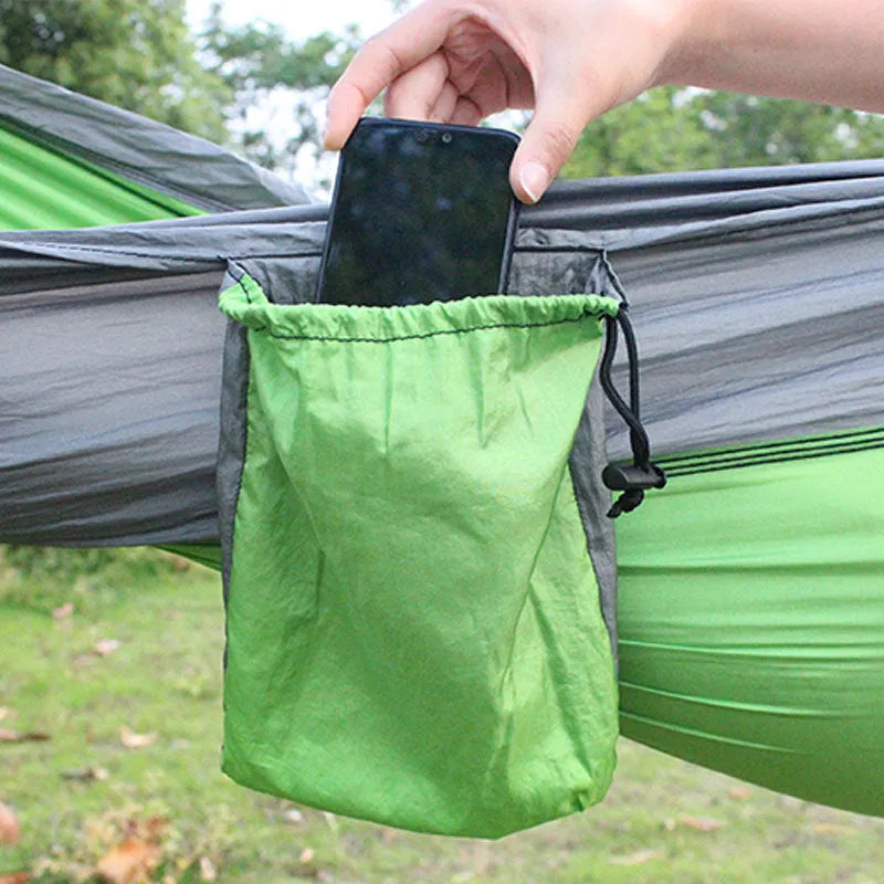 Blue parachute nylon camping hammock hung between two trees, showing its full 270cm length and attachment carabiners.