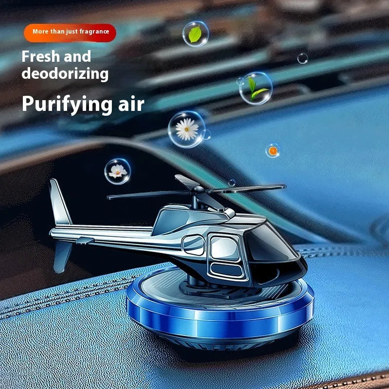 Silver metal solar-powered helicopter car air freshener rotating on a dashboard
