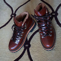 Men's brown leather city hiking boots with lace-up closure on a wooden surface