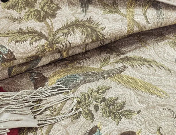 Blue American-style floral and bird quilted cotton bedspread set on a bed, showing textured stitching.