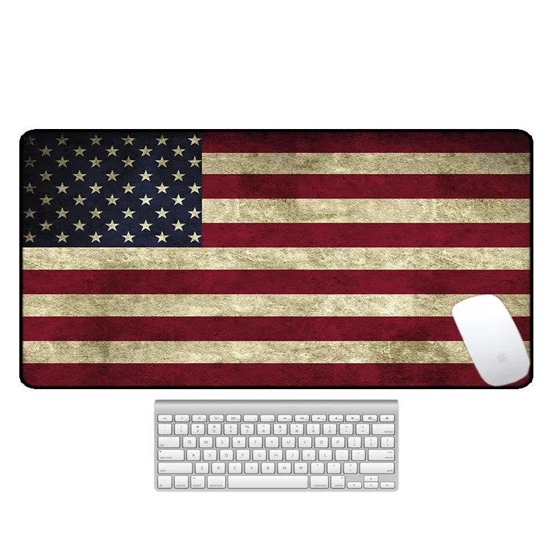 Large printed desk mouse pad with natural rubber non-slip base, shown on a wooden desk.