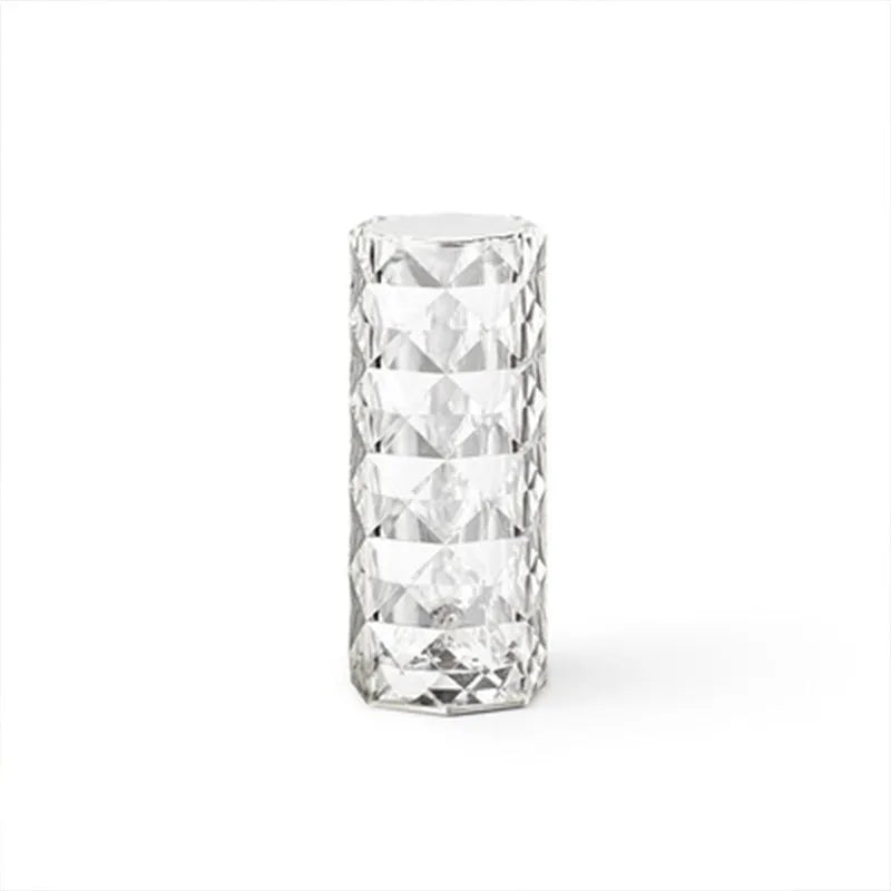 Clear acrylic crystal rose shaped LED table lamp with diamond-like facets on a table.