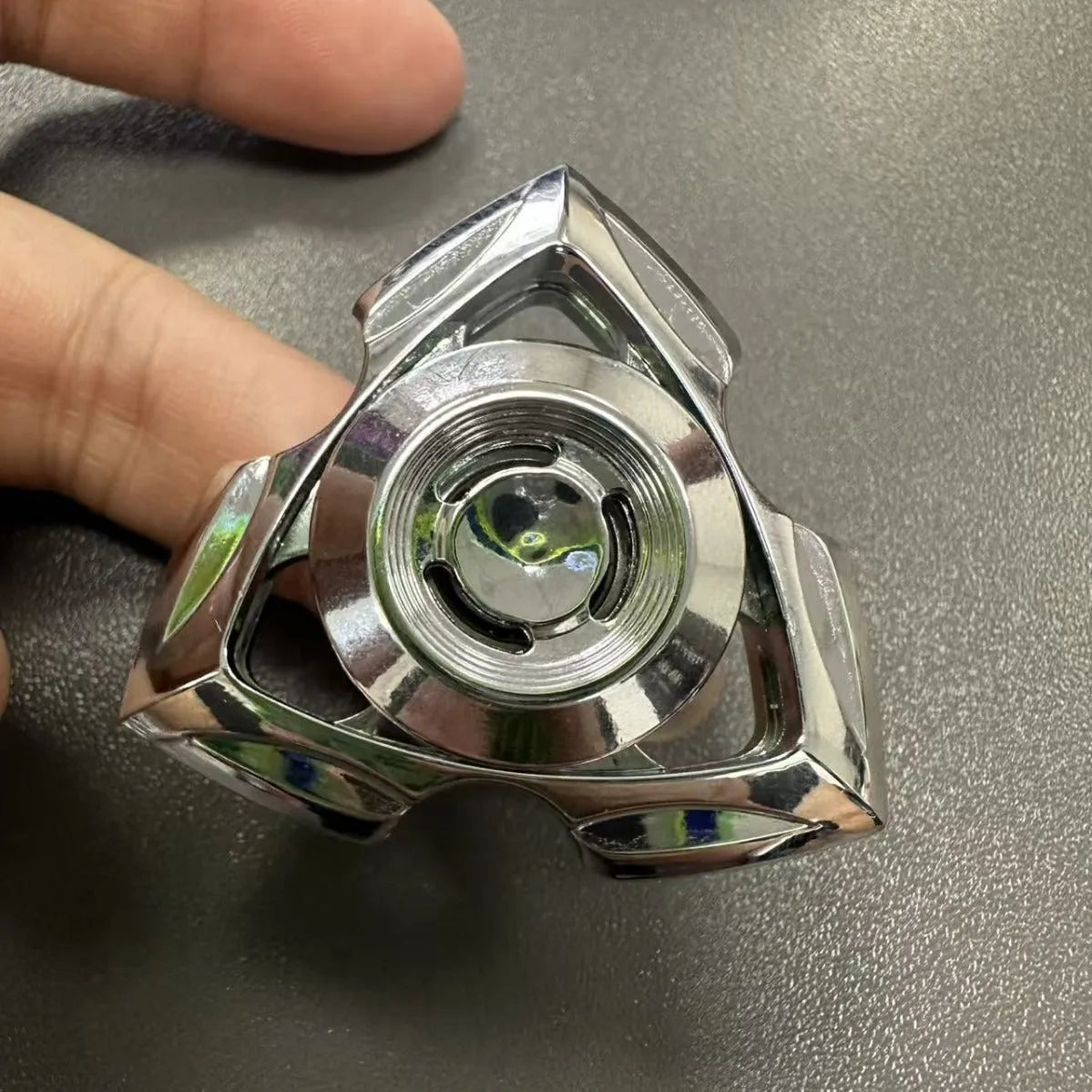 Silver and colourful alloy fingertip gyro decompression fidget toy on a plain background.