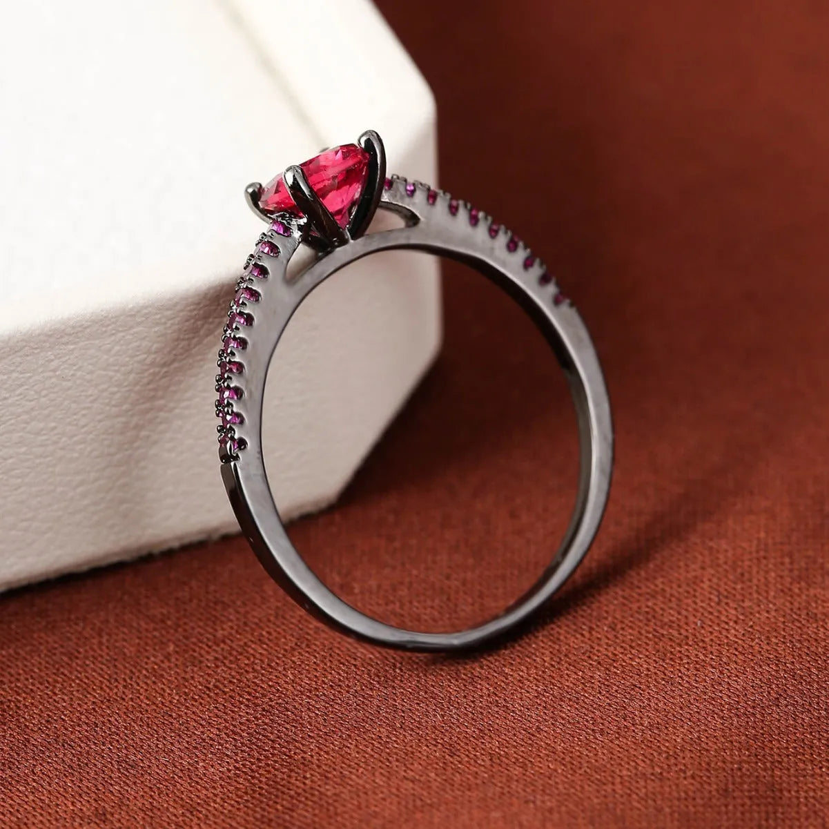 Geometric hexagonal copper ring with a zircon stone, shown in a gold rose red electroplated finish on a size 7 finger.