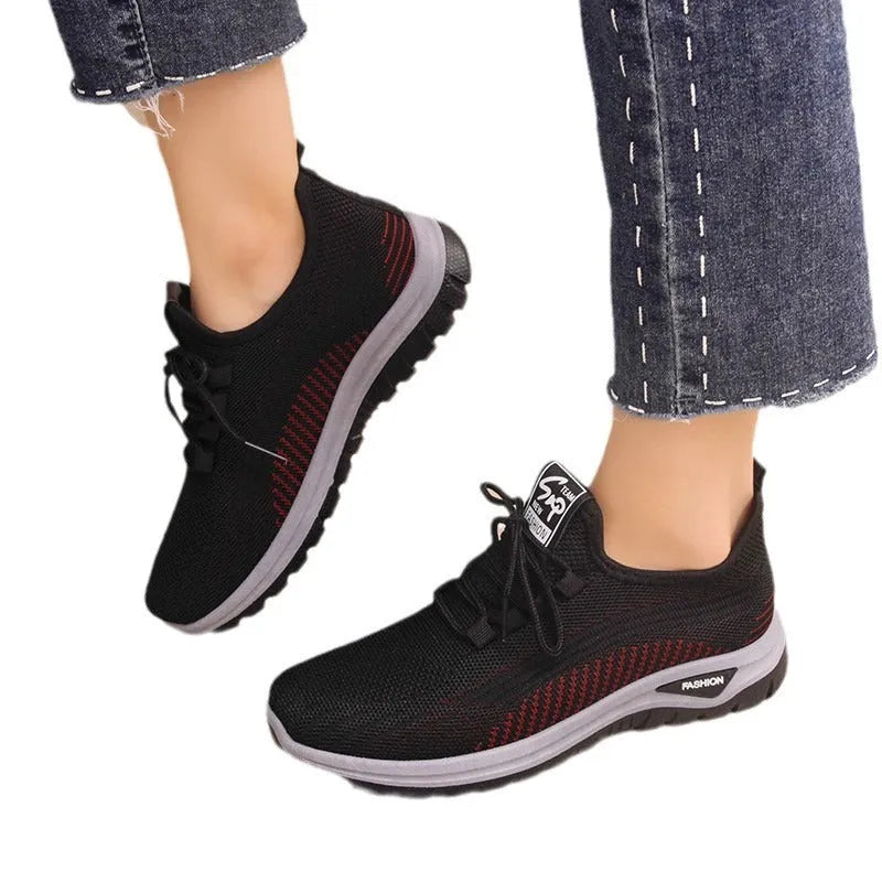 Women's black mesh sneakers with cross-strap detail and round toe on a rubber sole.