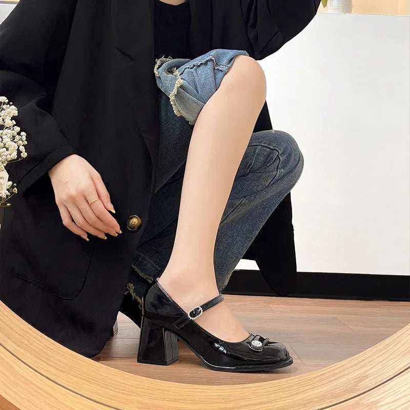 Women's black patent leather wide fit chunky heel shoe with round toe and buckle fastening.