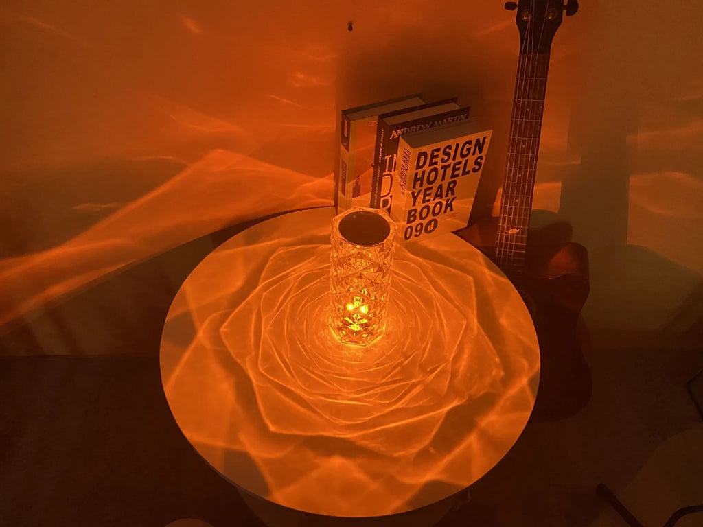 Clear acrylic crystal rose shaped LED table lamp with diamond-like facets on a table.