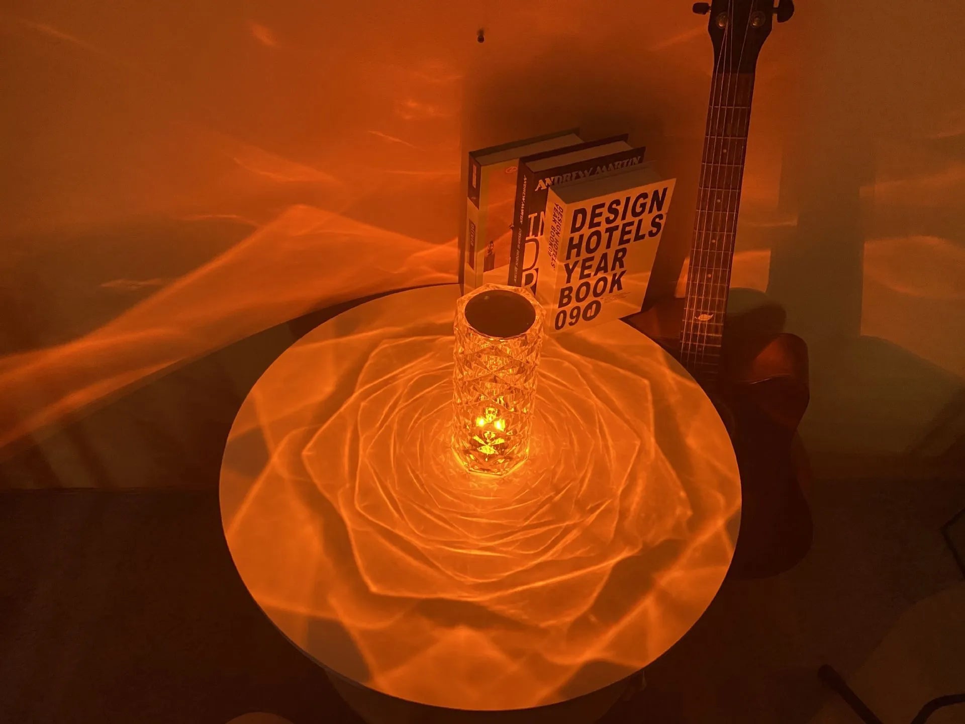 Clear acrylic crystal rose shaped LED table lamp with diamond-like facets on a table.