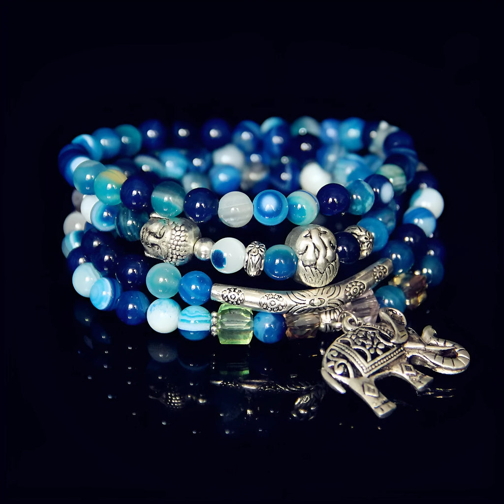 Multi-layer agate bracelet with blue elephant pattern amulet on a wrist.