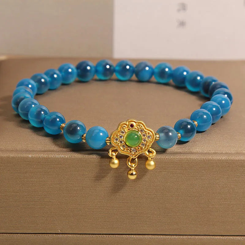 Blue sugar heart agate safety lock pendant on women's bracelet with alloy inlay and crystal accents.