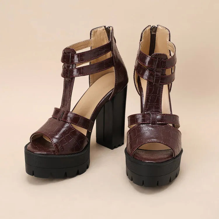 Black platform high heel sandals with a round toe and back zipper on a wooden floor.