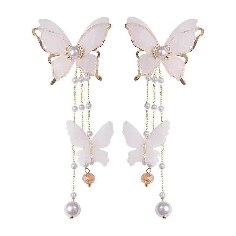 White butterfly shaped earrings with lace metalwork, a dangling tassel, pearl accents, and sparkling rhinestones.