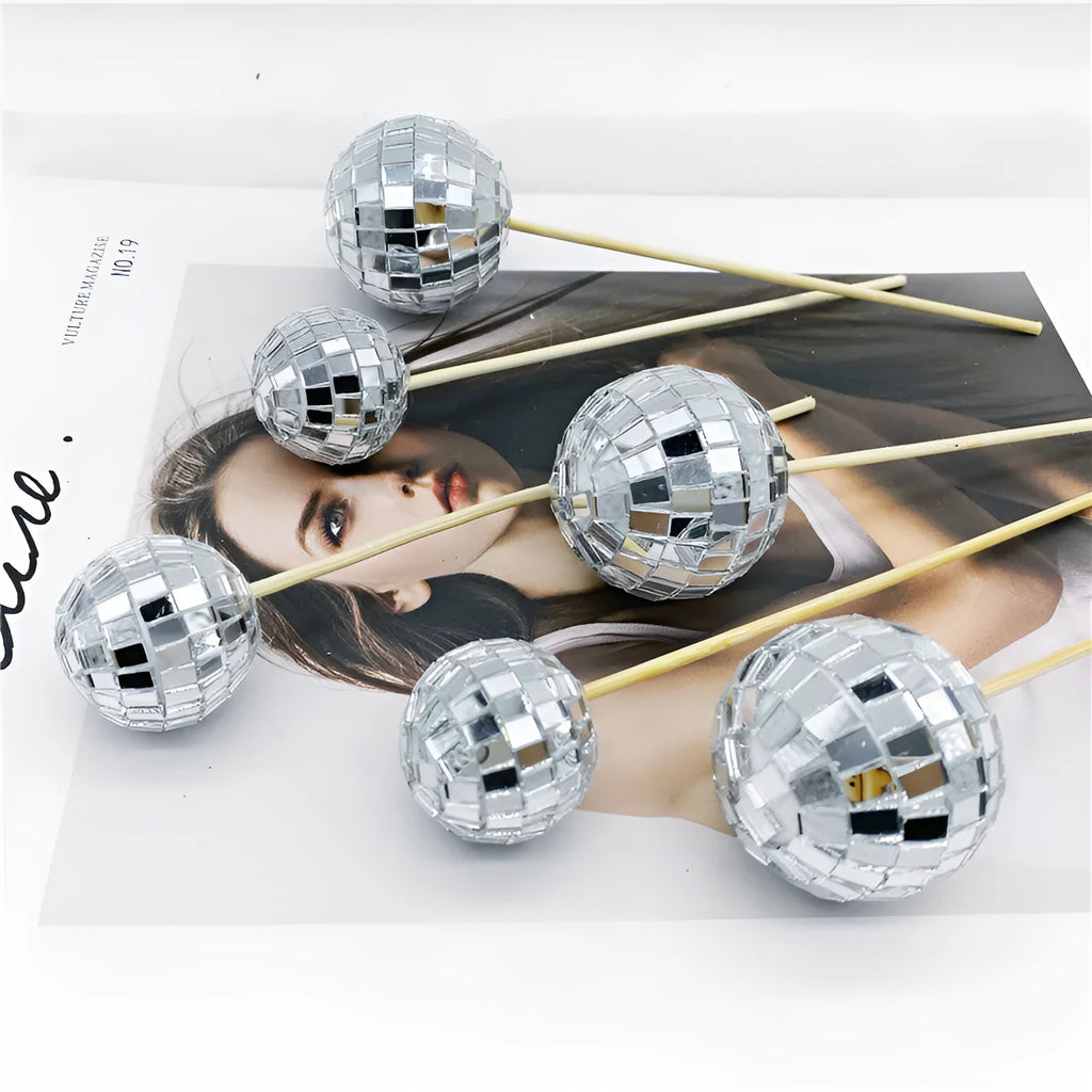 Small glass mirrored disco ball cake decoration attached to a thin wooden stick.