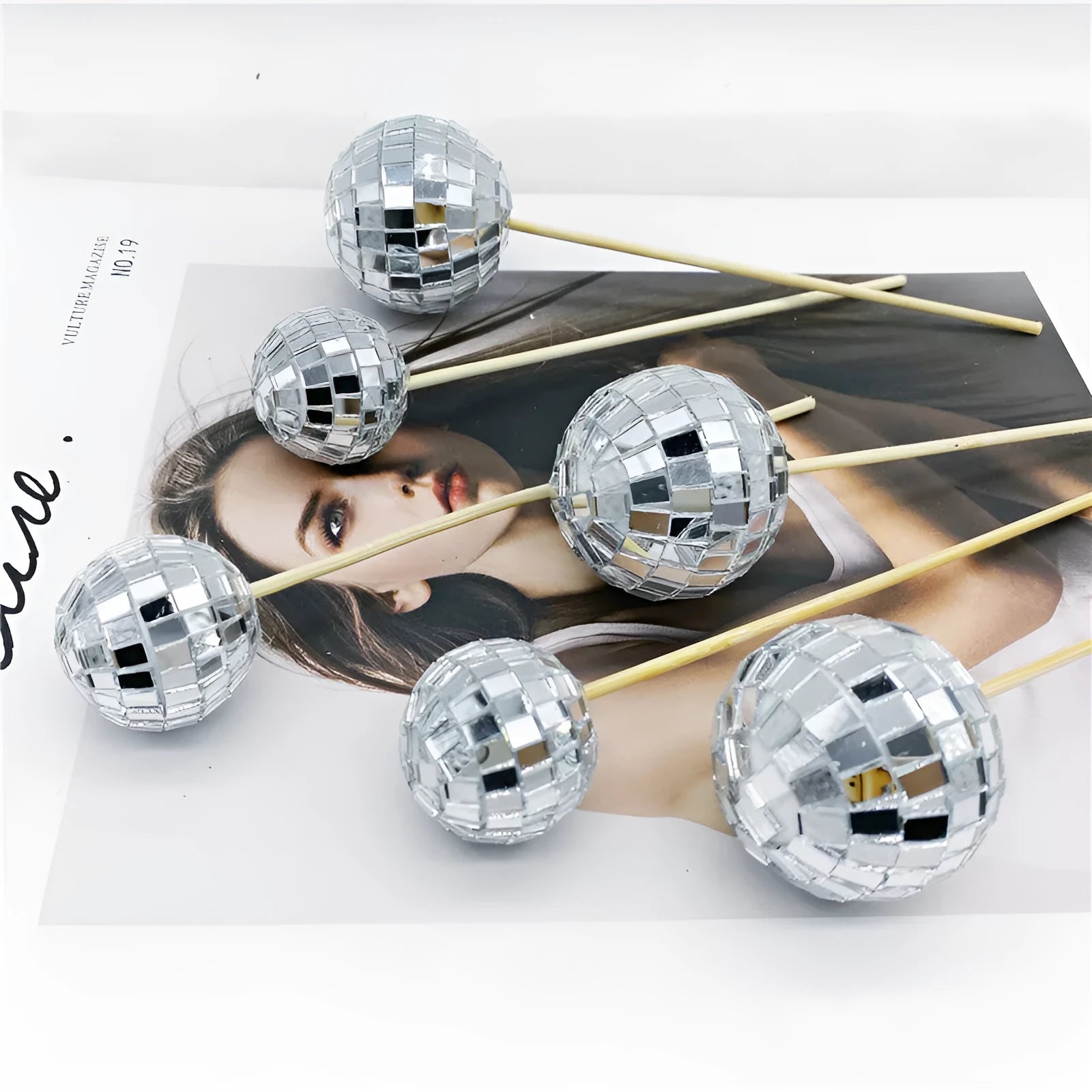 Small glass mirrored disco ball cake decoration attached to a thin wooden stick.
