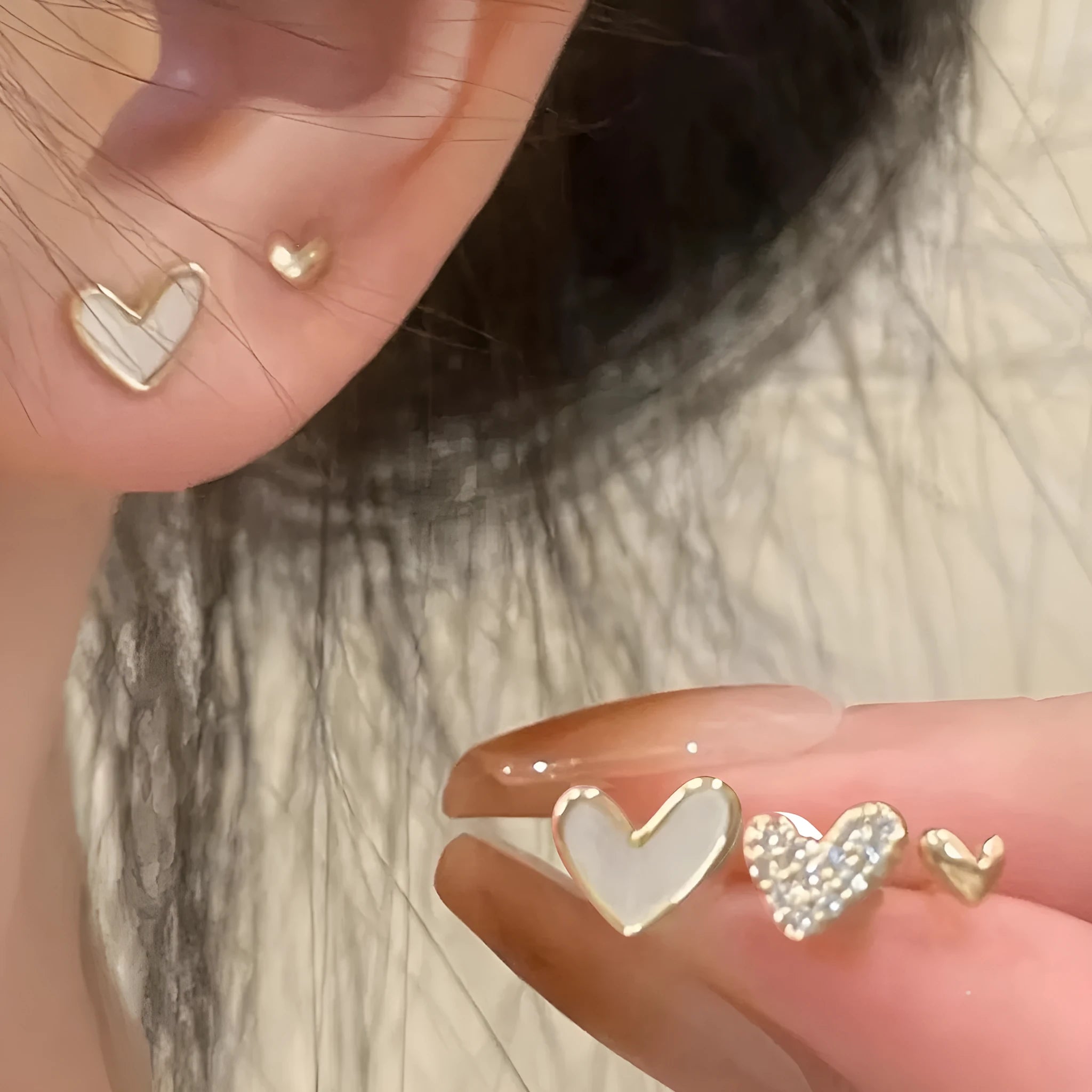 Three pairs of heart-shaped earrings in gold, black, black-white, and pink colours on display