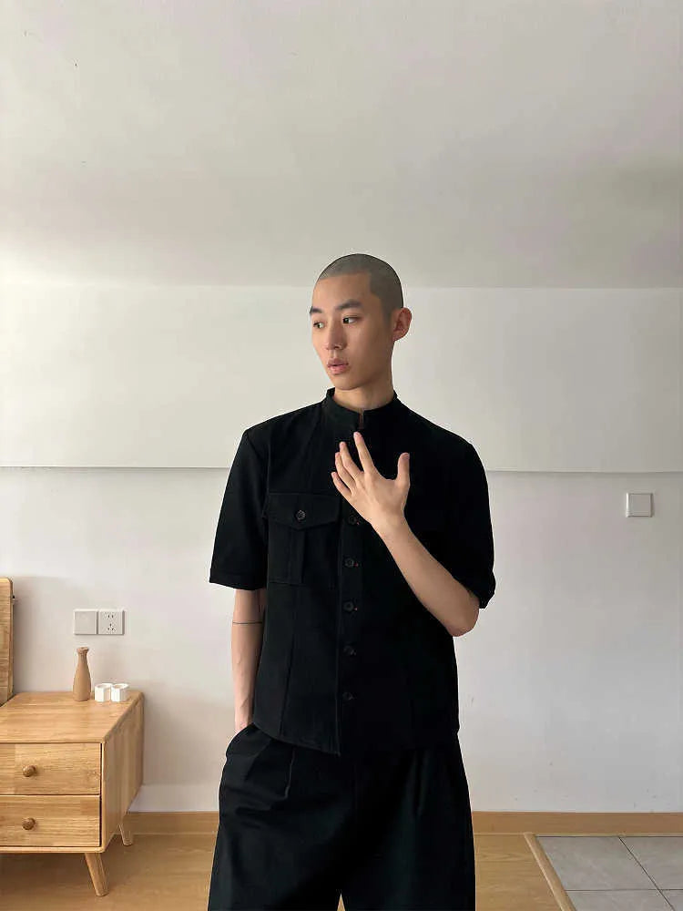 A black loose fit half sleeve hunting shirt with a shirt collar on a hanger.