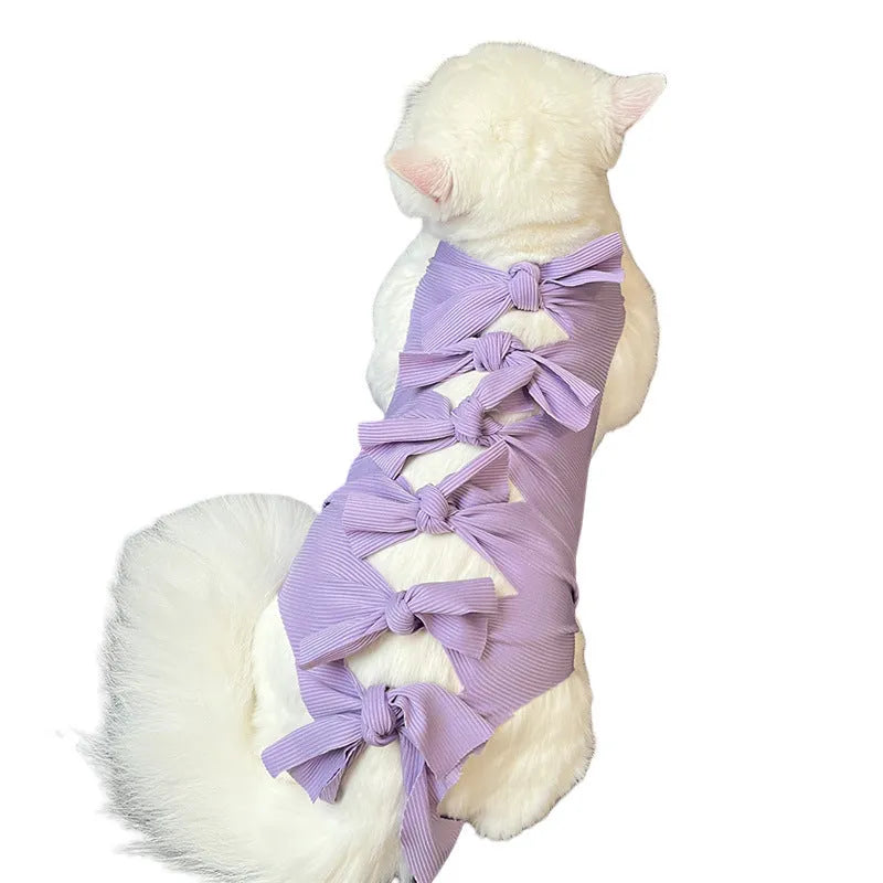 Pink lace-up cat recovery bodysuit on a table, showing back ties and full-body design for post-surgery care.