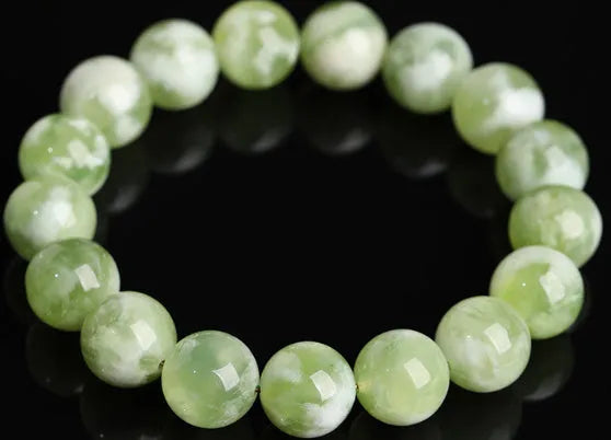 Green milk-in-water Xiuyan jade bracelet with geometric beads on white background