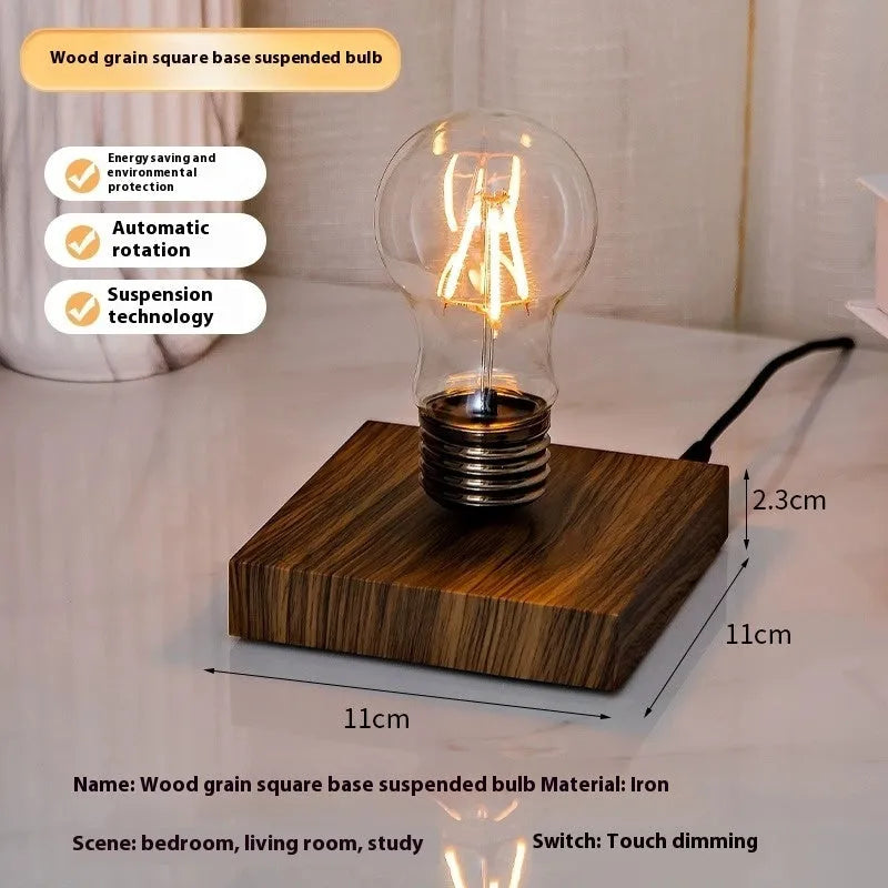 Small black suspension bulb night lamp with an iron art base on a wooden desk.