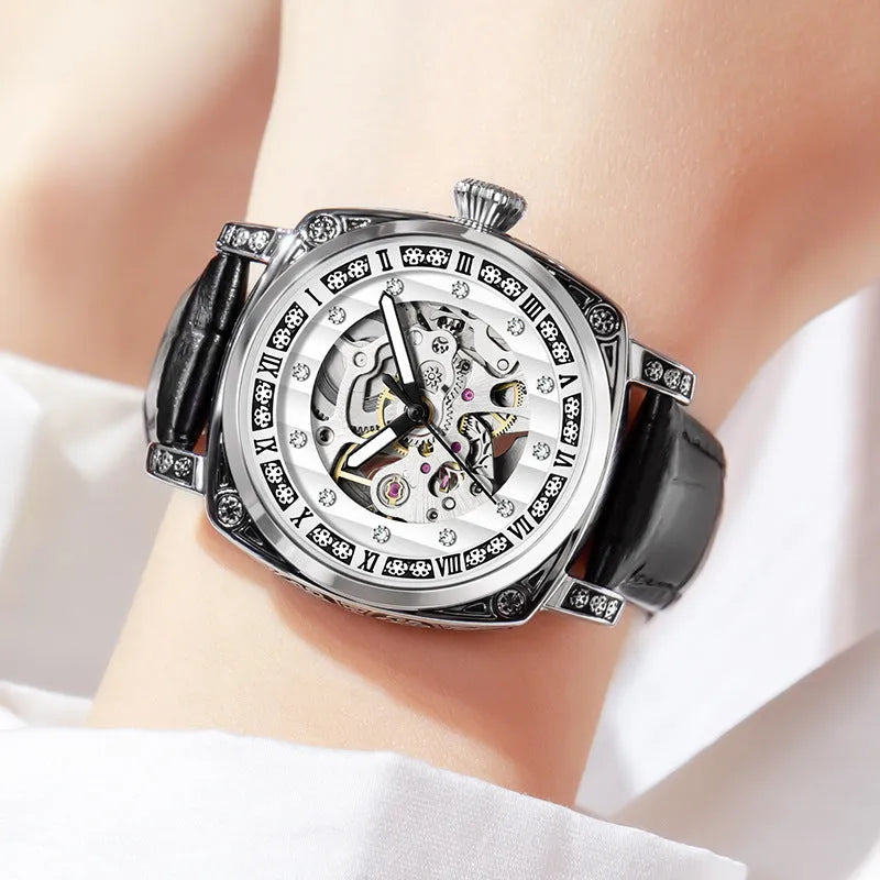 Men's black leather strap mechanical watch with luminous hands on a wrist.