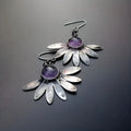 A pair of purple resin bohemian earrings with alloy details and animal or floral modelling on a white background.