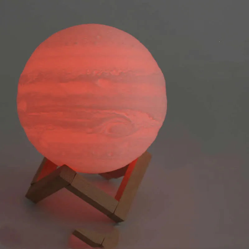 3D printed white moon lamp on a wooden holder, showing detailed lunar surface and a glowing yellow light.