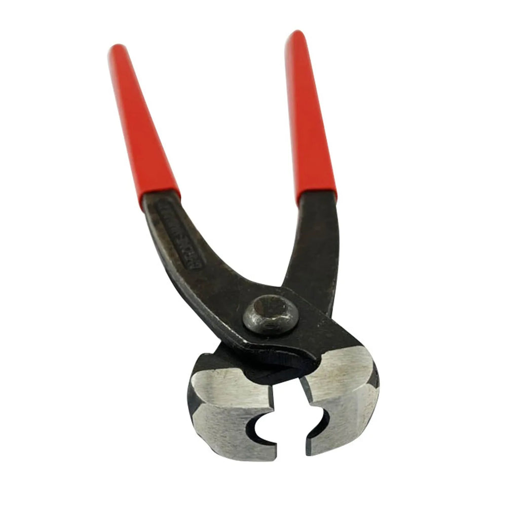 Red cloth finished metal single ear hose clamp next to a carbon steel cutting tool on a workbench.