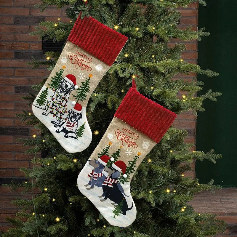 Red and green cloth Christmas stocking pendant for pets, hanging on a tree branch.