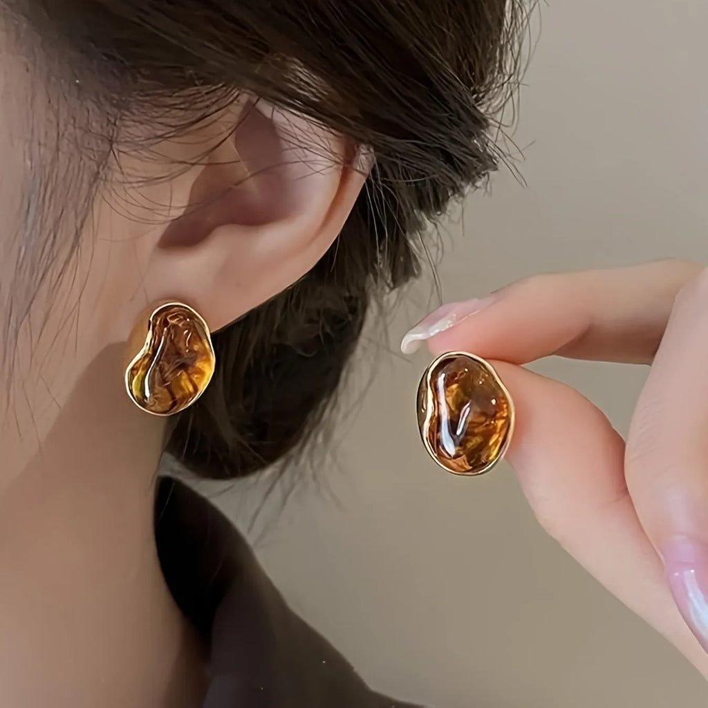 Set of three pairs of geometric holiday earrings: round studs, irregular amber studs, and tassel drop earrings.