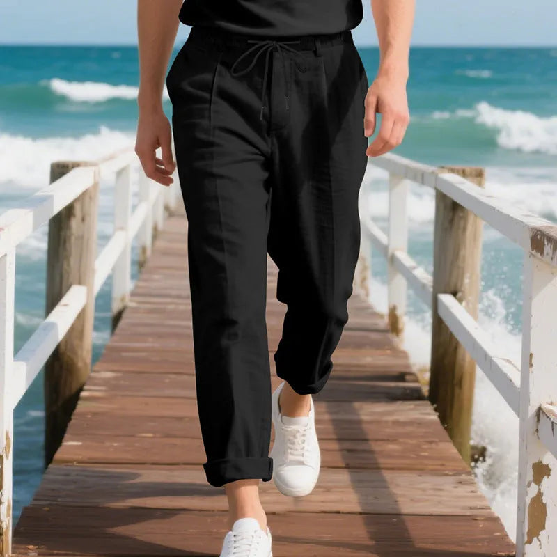 Man wearing light khaki linen casual trousers with a drawstring waist and straight-leg fit.