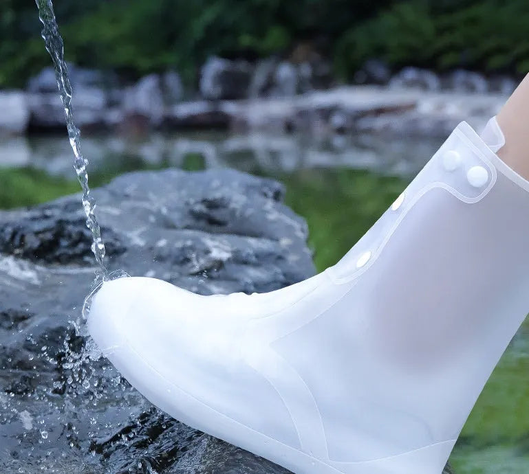 White high-top reusable PVC waterproof shoe covers with anti-skid sole on a wet surface.