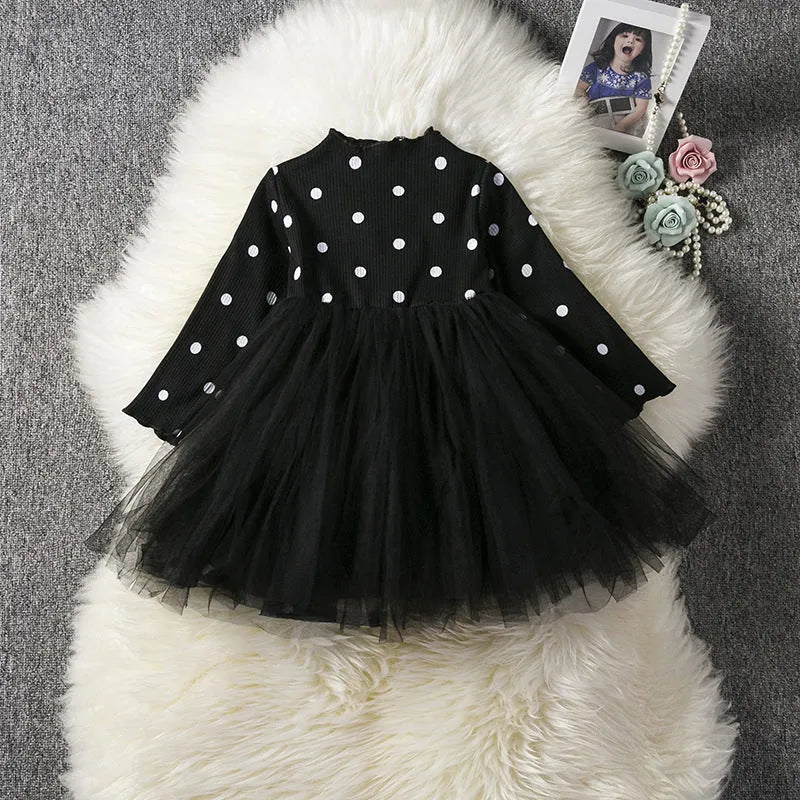Baby girl wearing a long sleeve black tutu lace dress for a first birthday party.