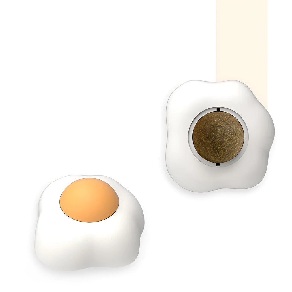 Catnip ball toy with adhesive backing attached to wall, showing cat head shape design