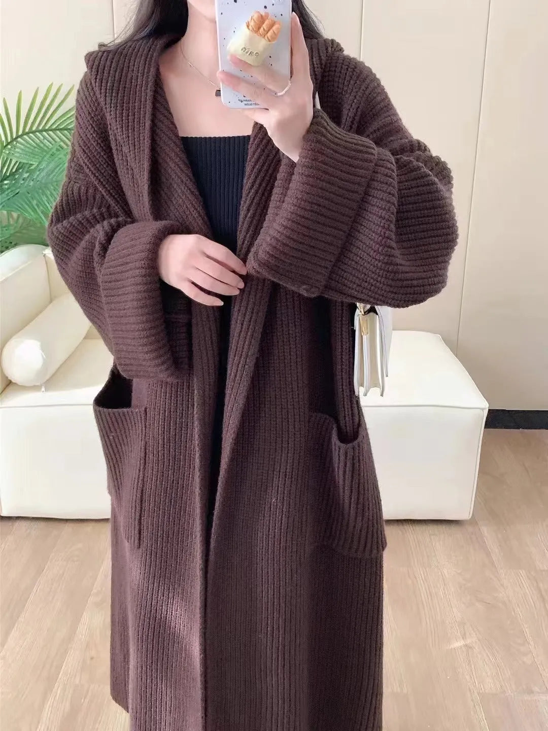A woman wearing a loose, milky white hooded cardigan coat with raglan sleeves.
