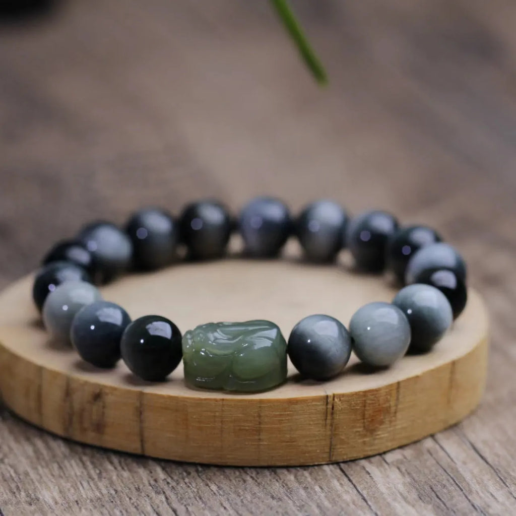 Black 10mm Eagle Eye Stone bracelet with a natural Hetian Jade Pixiu charm showing a clear water pattern.