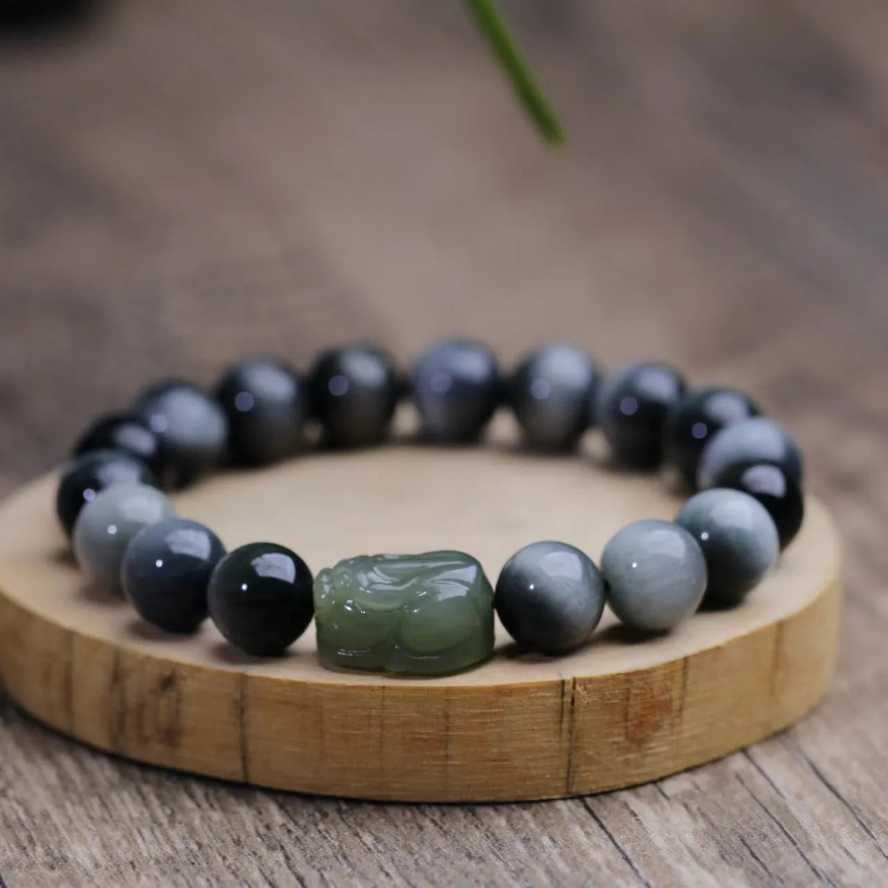 Black 10mm Eagle Eye Stone bracelet with a natural Hetian Jade Pixiu charm showing a clear water pattern.