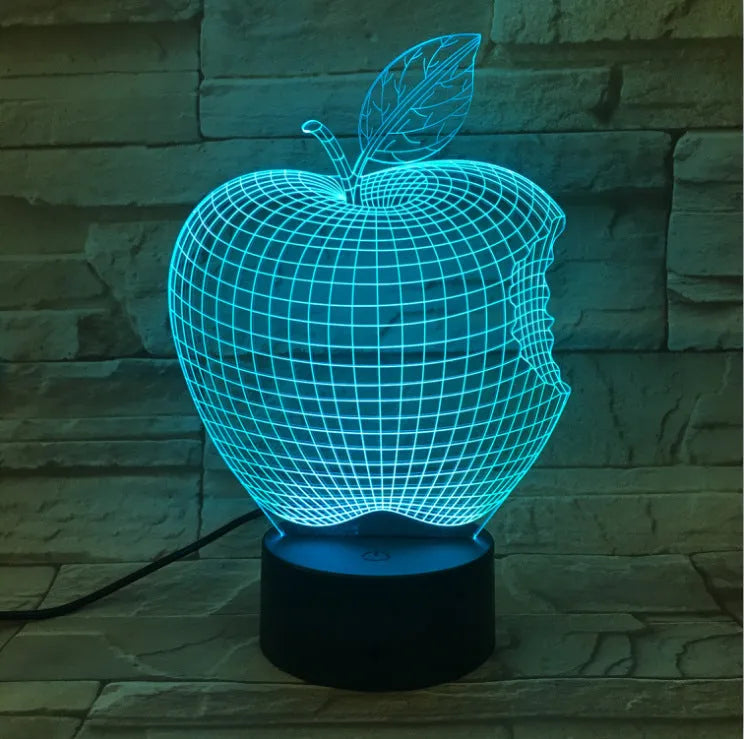 3D fruit-shaped colourful acrylic night light with touch control on a dark surface.