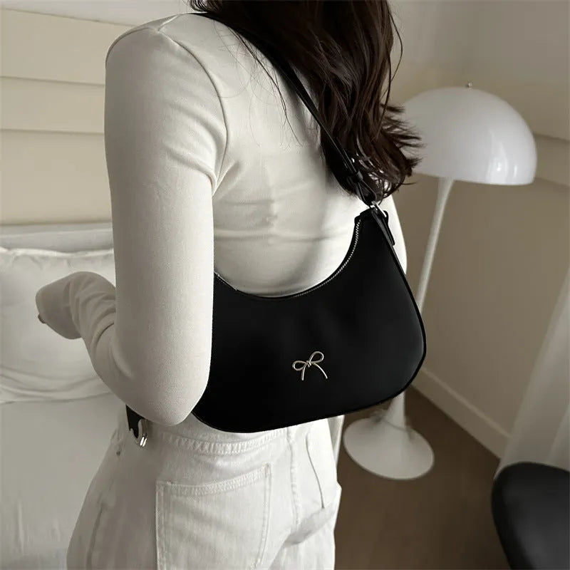 Women's black dumpling-shaped PU shoulder baguette handbag with a single strap and sewing thread detail.