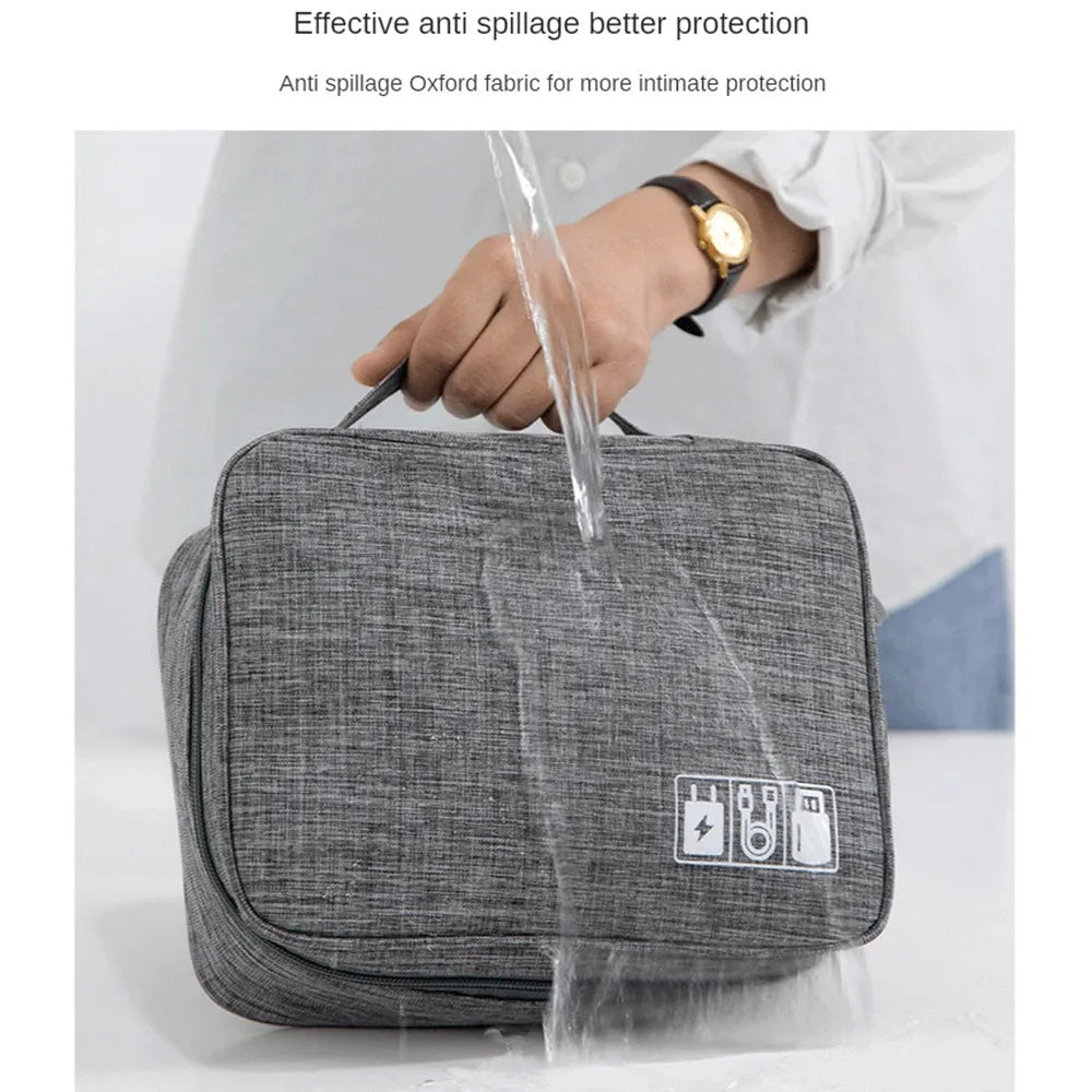 Black waterproof electronics organiser bag open, showing mesh pockets, elastic loops, and removable padded dividers inside.