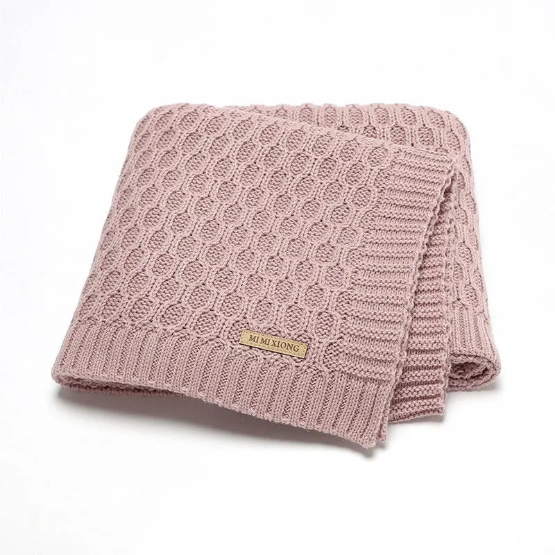 Solid colour acrylic infant blanket with textured lines, shown in a selection of colours including pink and grey.
