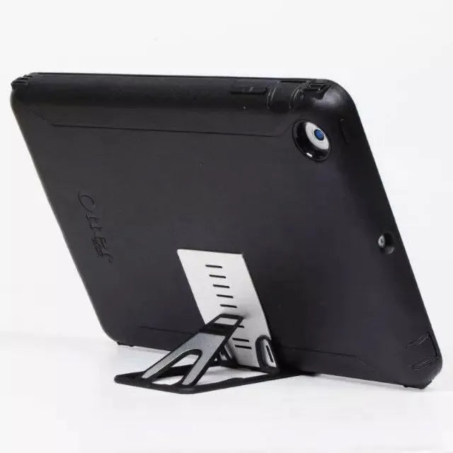 Black desktop card phone holder on a wooden desk next to a mobile phone and credit cards