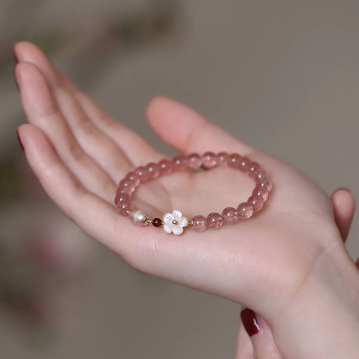 Women's strawberry quartz crystal flower bracelet showing peach blossom charm bead detail