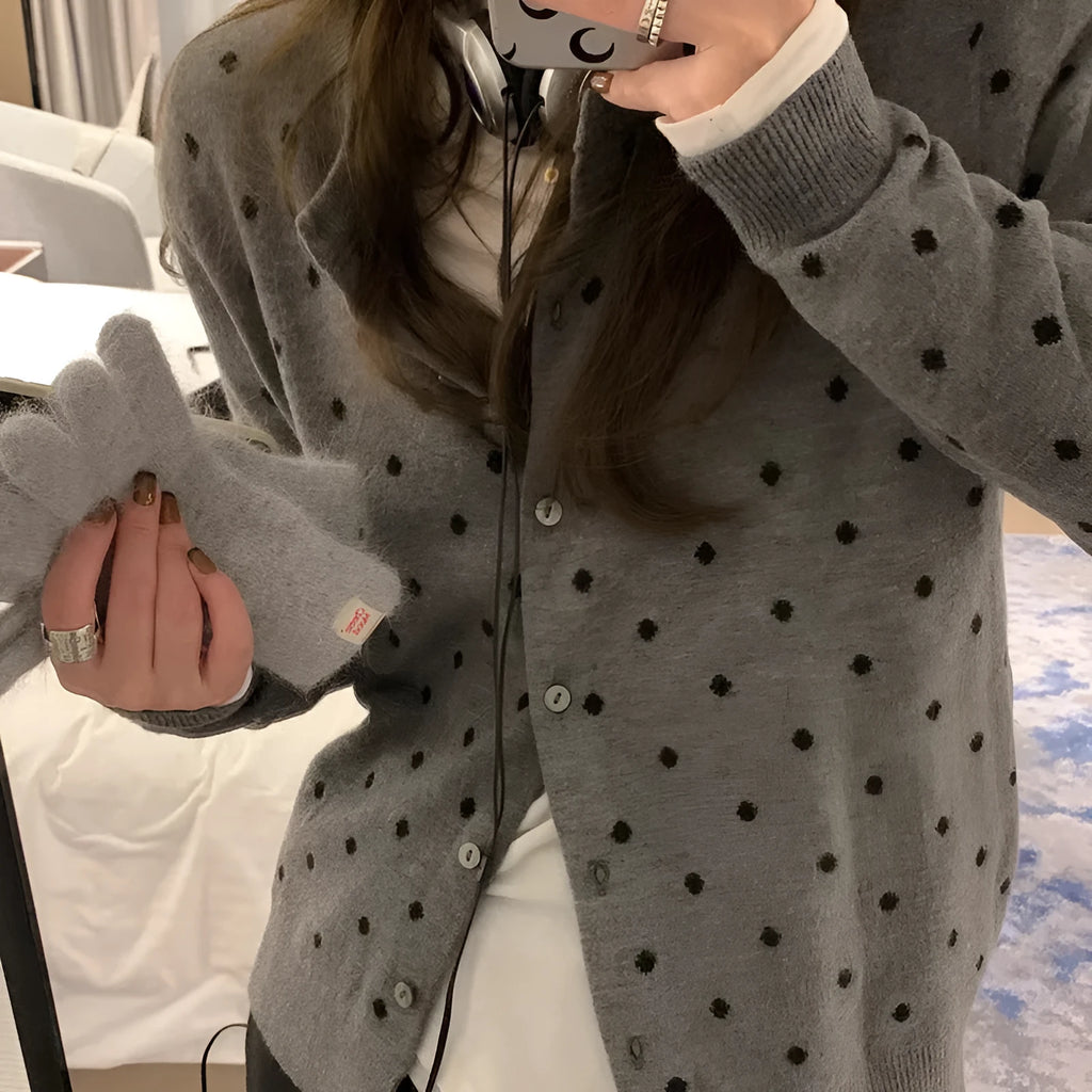 Women's loose grey dot patterned knitted cardigan with crocheted flower details on the front.
