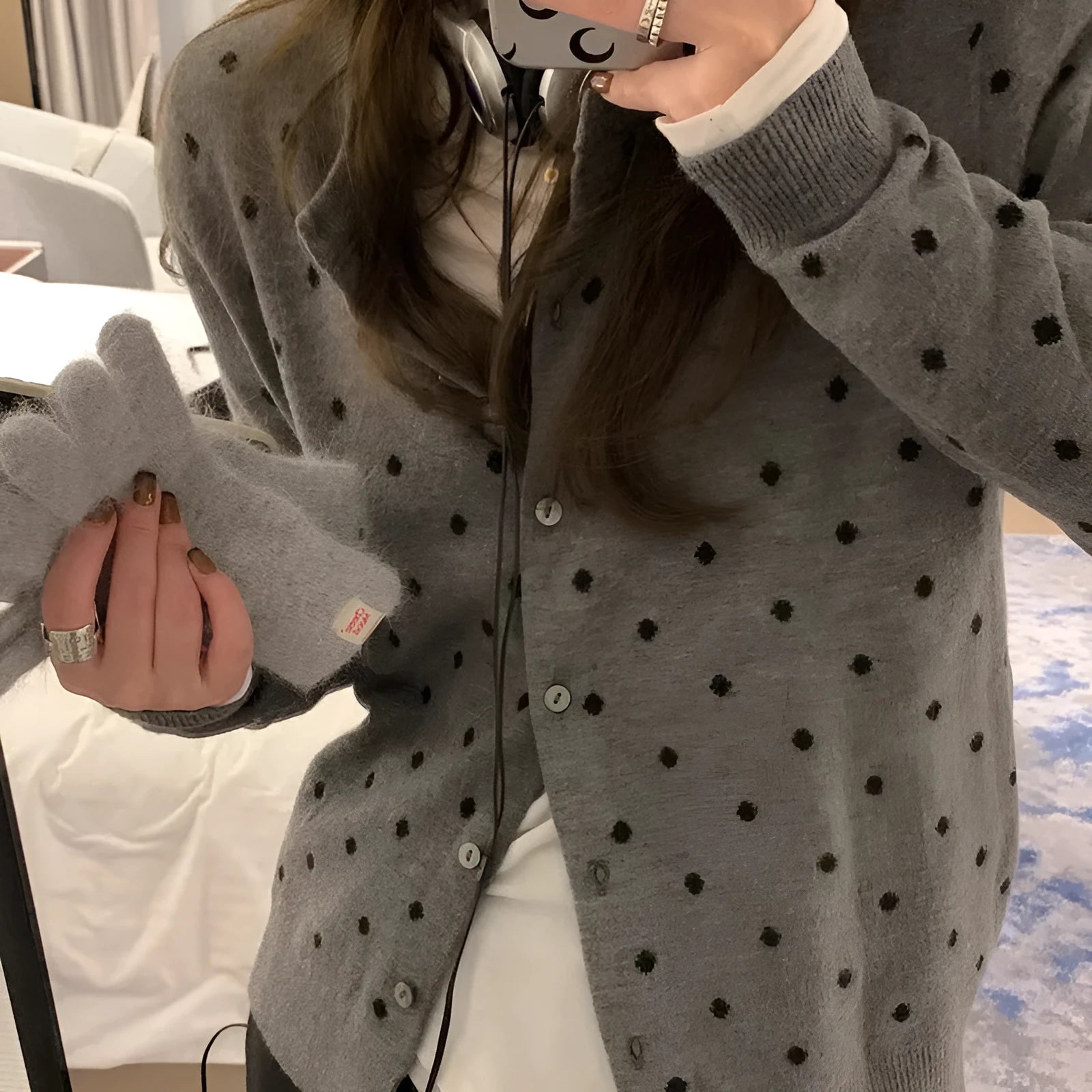 Women's loose grey dot patterned knitted cardigan with crocheted flower details on the front.