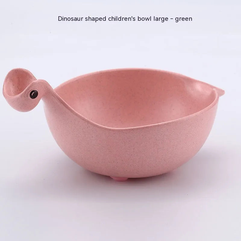 Three wheat straw dinosaur bowls in pink, green, and beige on a kitchen table