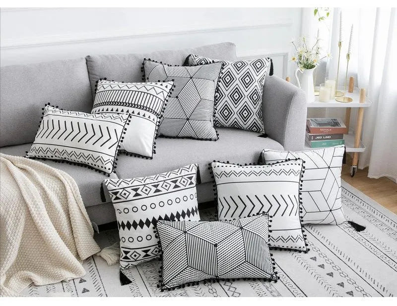 Bohemian style decorative throw pillow with polyester cover in light grey on a sofa.