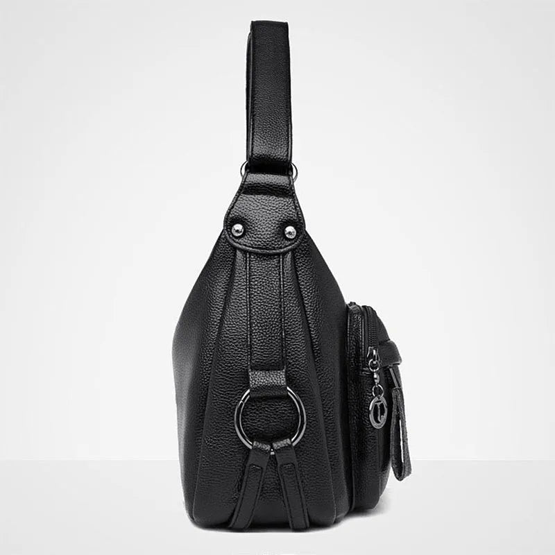 Blue horizontal square women's crossbody bag with a soft handle and zipper opening, showing organiser pockets inside.