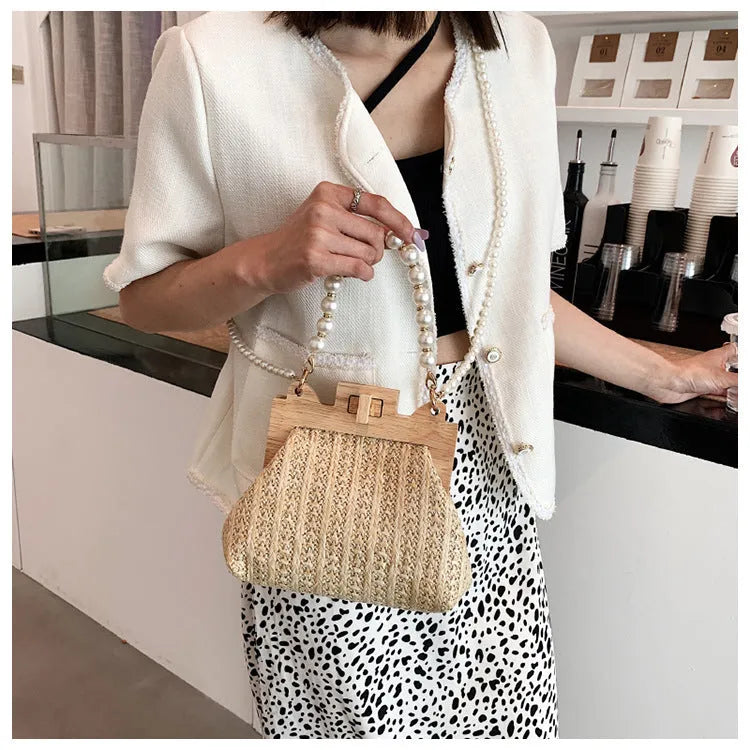 Women's woven straw shoulder bag with pearl chain detail showing horizontal square shape and multiple internal pockets