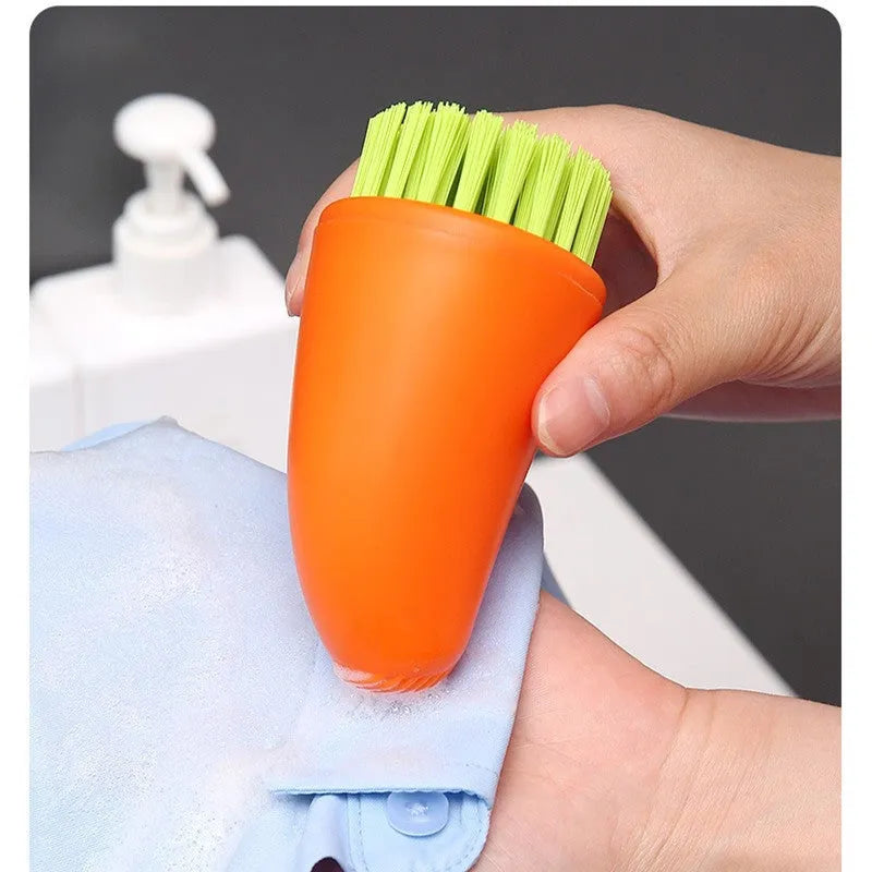 Orange and white carrot-shaped nylon kitchen cleaning brush on a plain background.